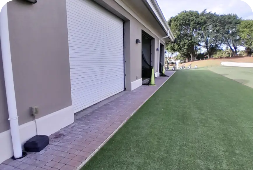 Side yard with artificial turf and brick path beside performance center