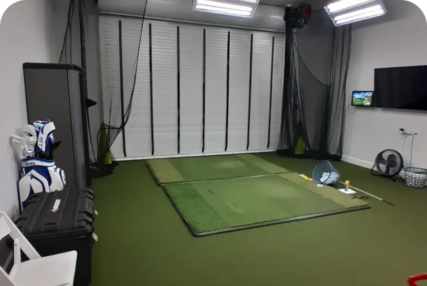 Golf simulator studio with hitting mat and wall-mounted monitor