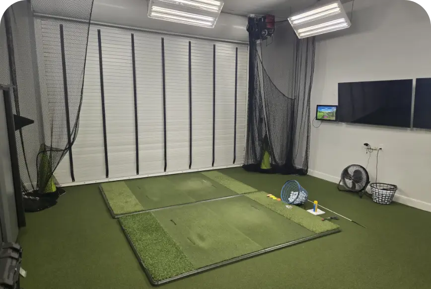 Indoor hitting bay with turf mat and launch monitor screen