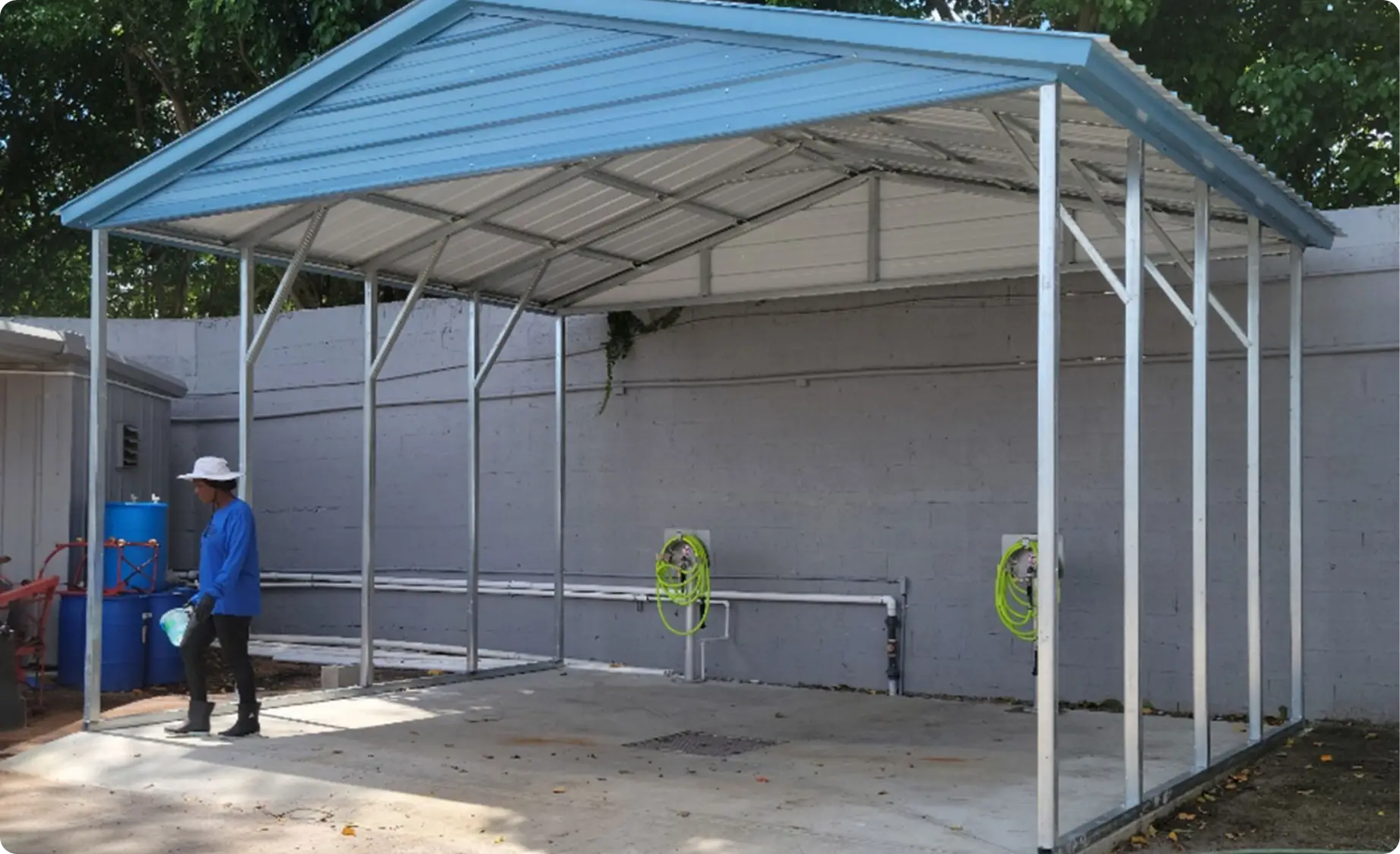 Open-sided steel wash rack with blue roof and hose reels