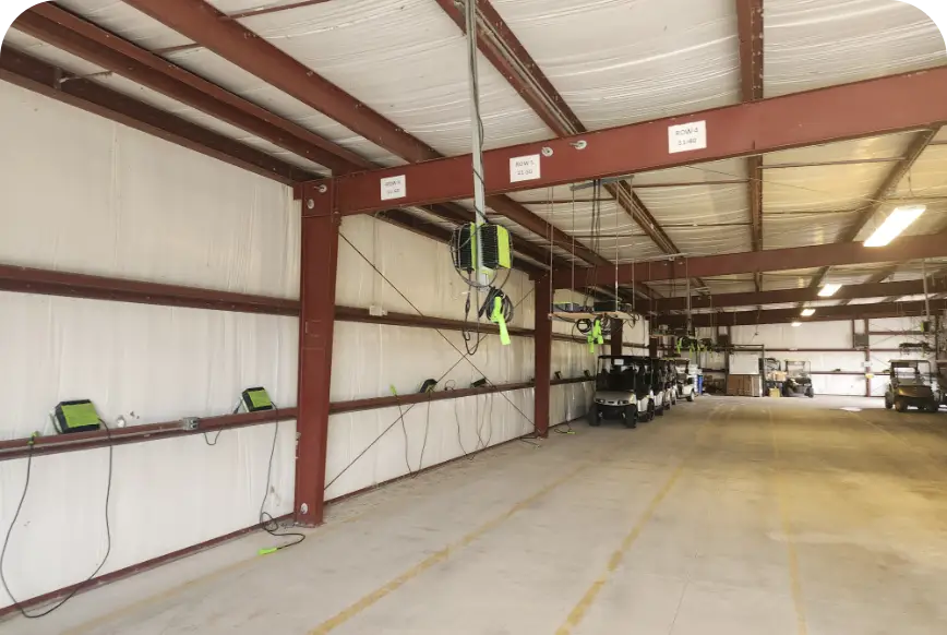 Open steel-framed bay of golf cart storage building with charger racks