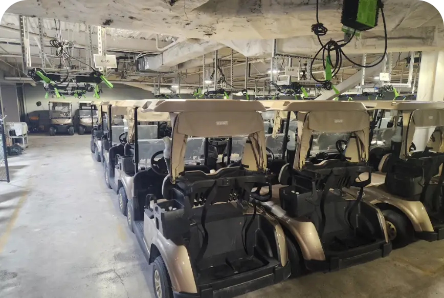 Rows of golf carts with overhead charging cables in storage barn