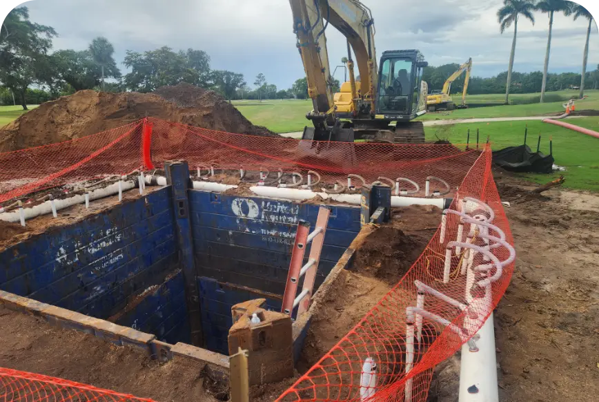 Excavator beside braced trench at golf course pump station dig site