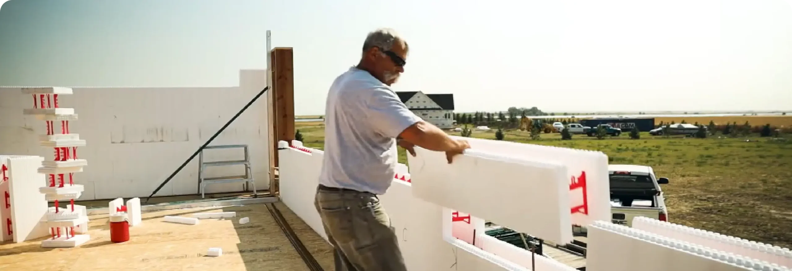 Worker setting insulated concrete form blocks on slab edge
