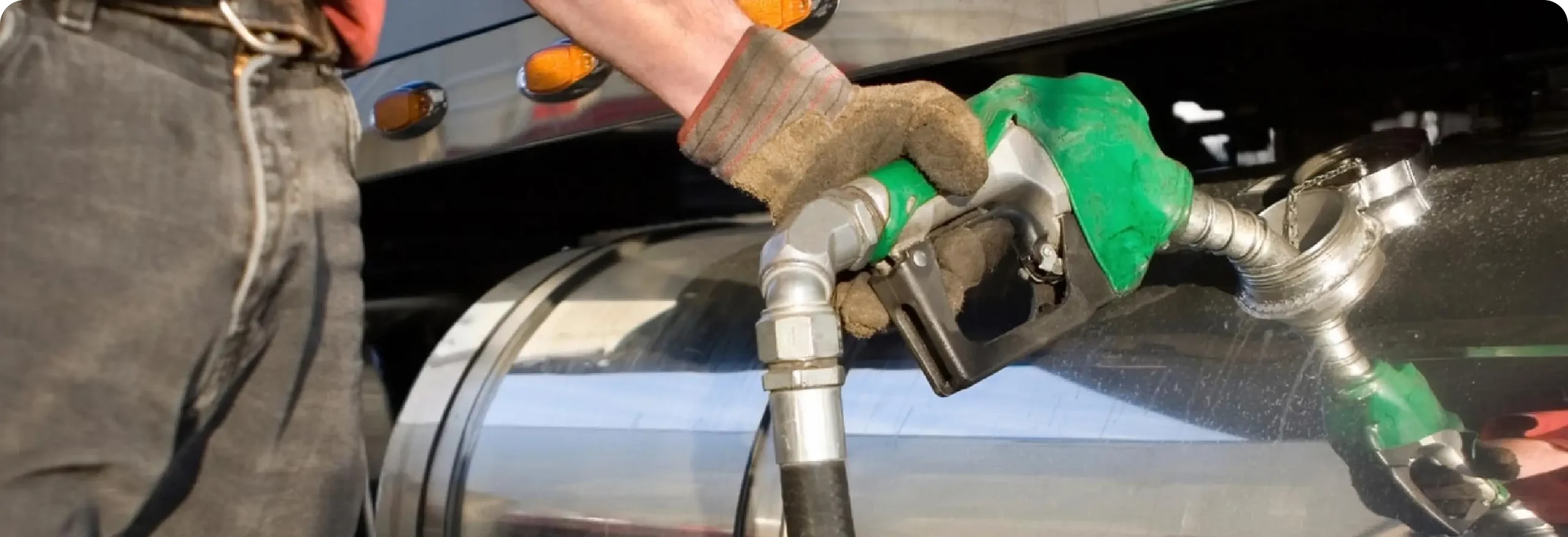 Worker fueling equipment from diesel tank with green nozzle