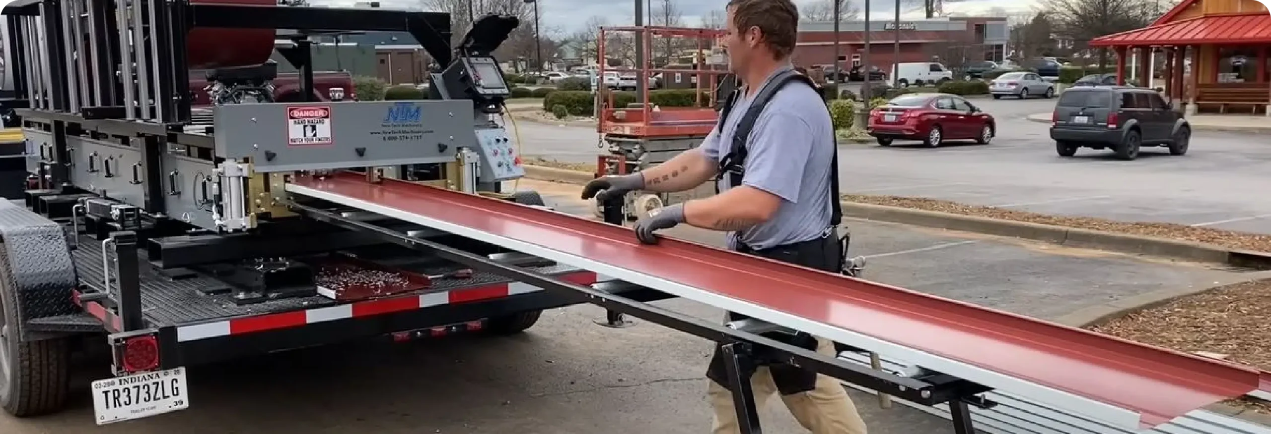 Worker loading red steel roof panels onto flatbed truck