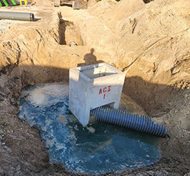 Concrete drainage structure set in excavated site with corrugated pipe