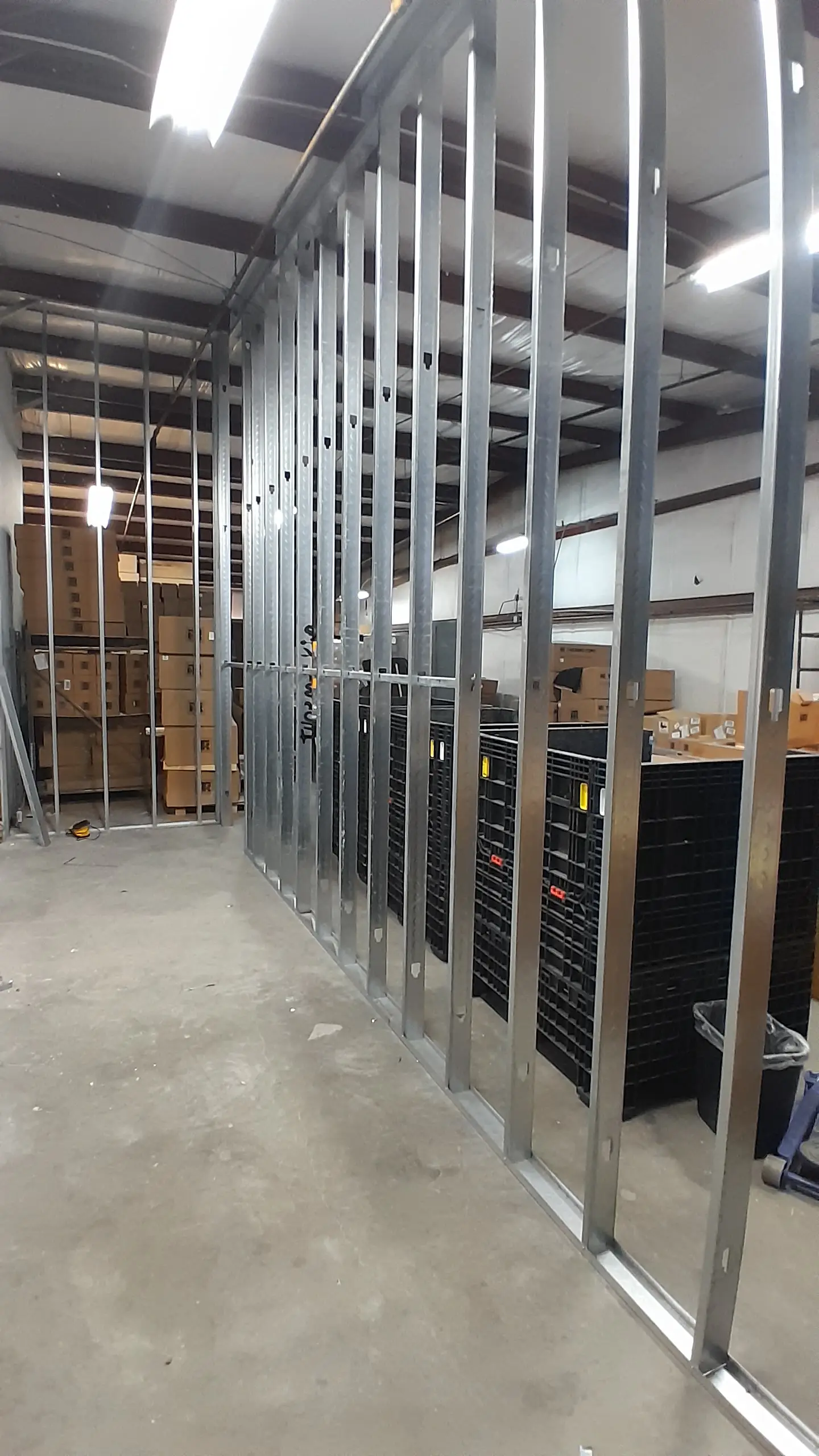 Metal-stud wall framing along warehouse storage shelving