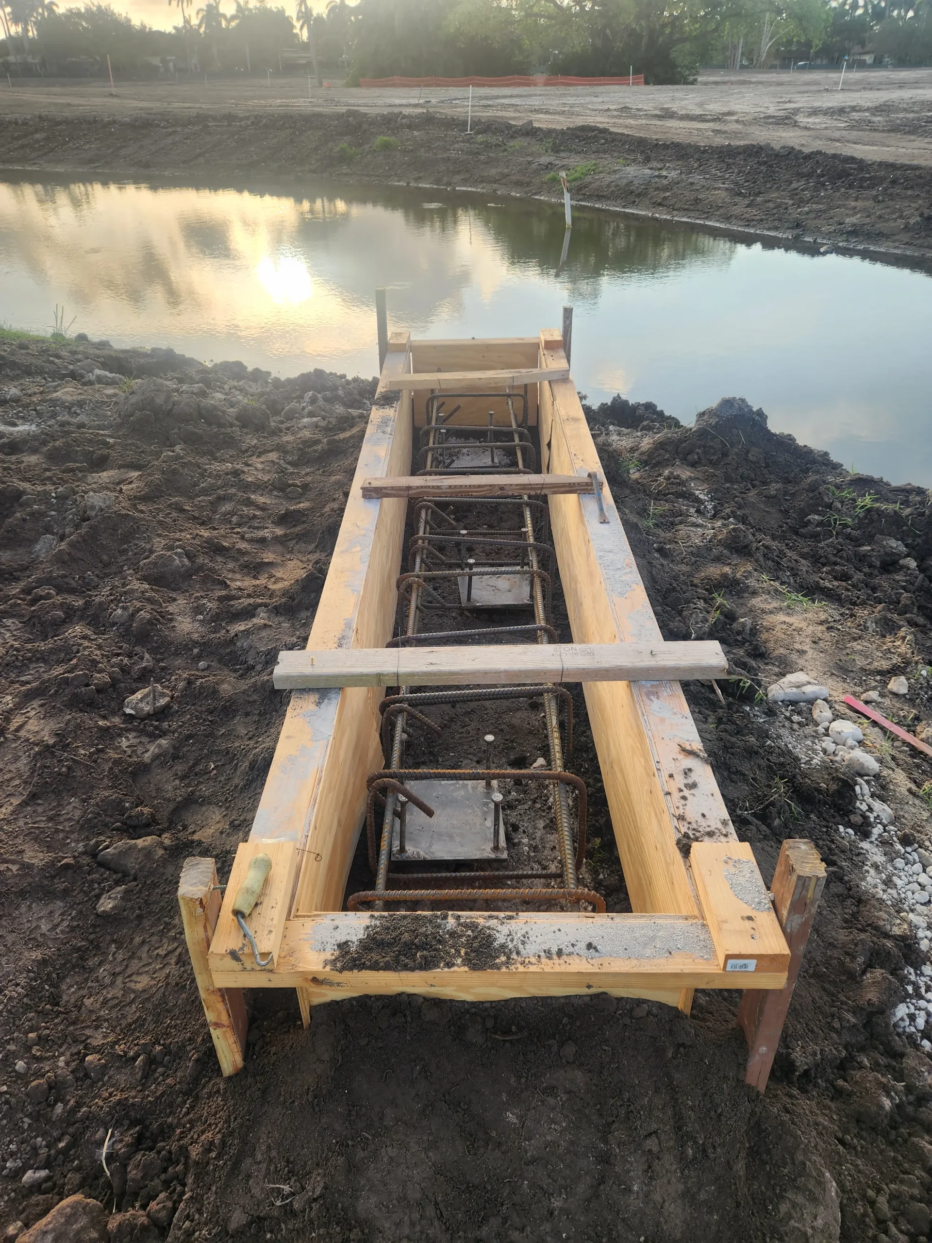 Formed concrete footing beside pond at golf course site