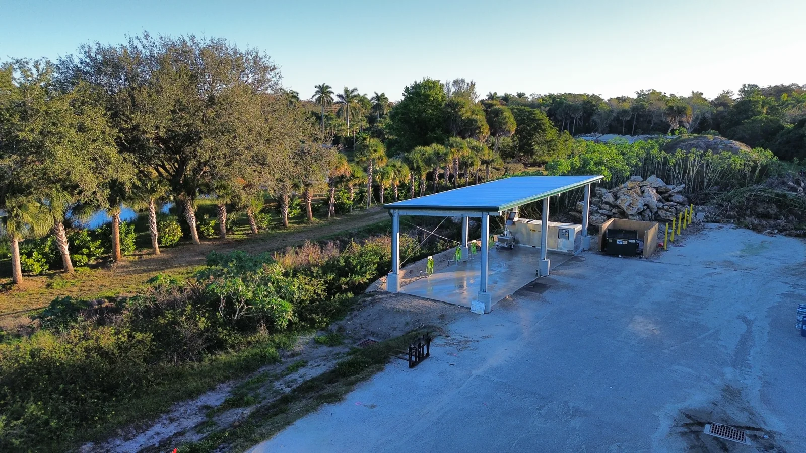 Aerial view of the finished covered wash pad at Hole in the Wall Golf Club, blue steel roof over a concrete pad surrounded by the golf course landscape