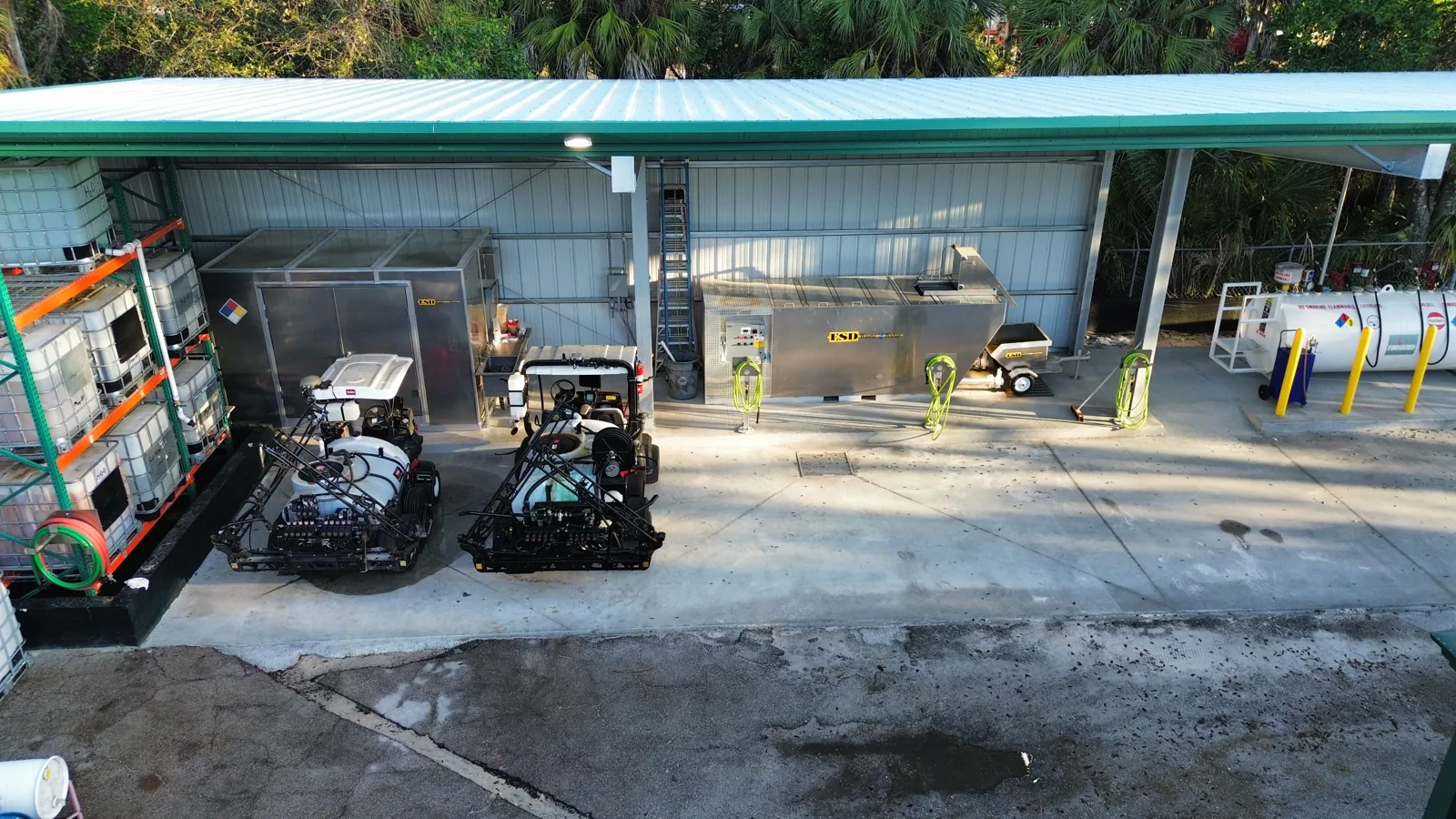 Aerial view of the completed Naples Heritage facility showing spray rigs parked under the covered wash pad, stainless wash station, and fuel area on freshly poured concrete.