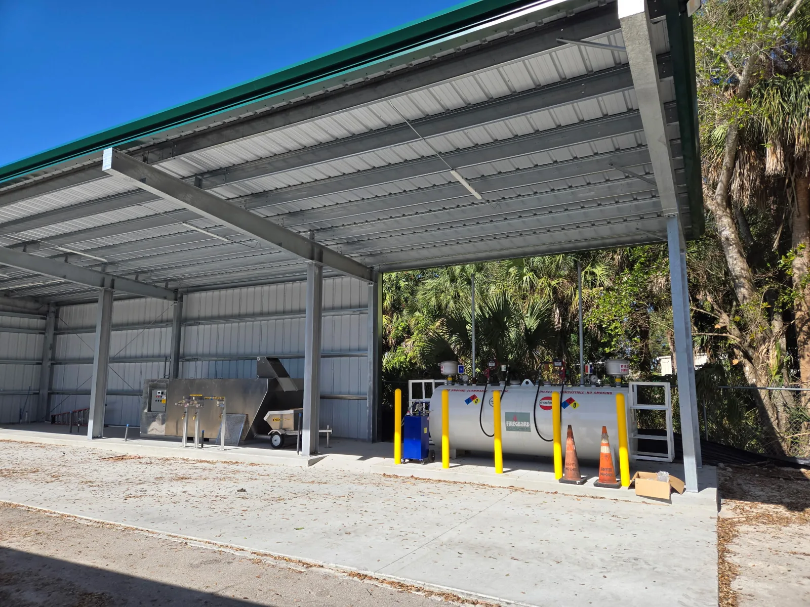 Completed steel canopy at Naples Heritage covering the fuel, wash, and mix load area, with a stainless mix station and fuel tank beneath the green-trimmed roof.