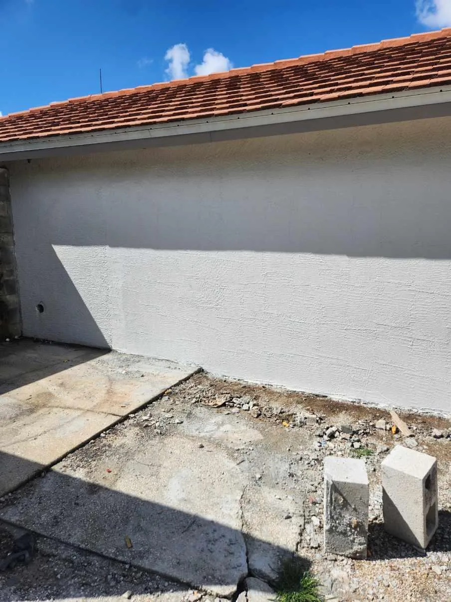 The rebuilt and refinished exterior wall of the Naples Heritage pump house, re-stuccoed and painted to match the existing structure with no sign of the opening.
