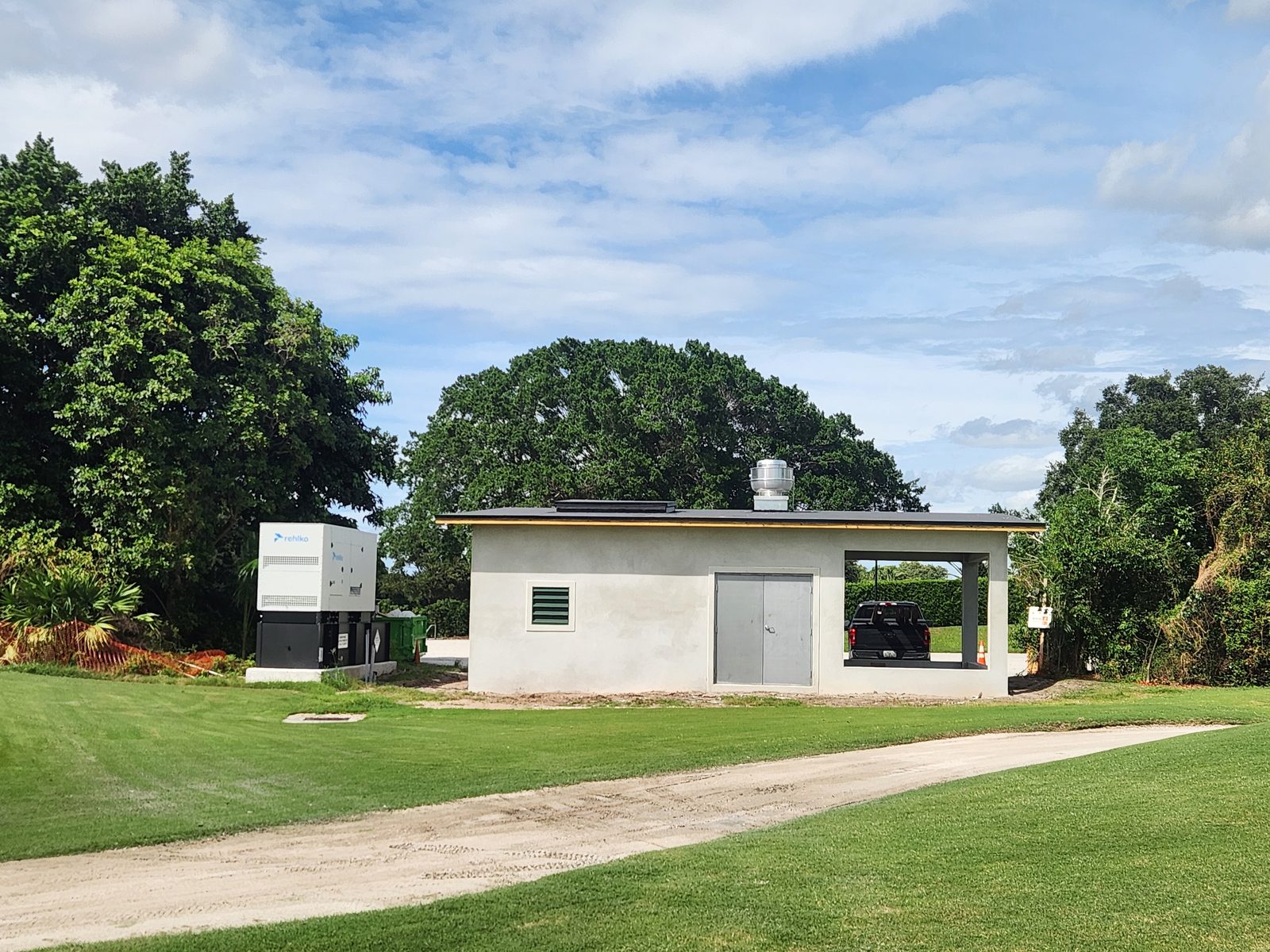 Completed irrigation pumphouse built by Roughneck Ranch at Pine Tree Golf Club in Boynton Beach, Florida, with an enclosed pump room, a covered acid-injection bay, and a standby generator alongside