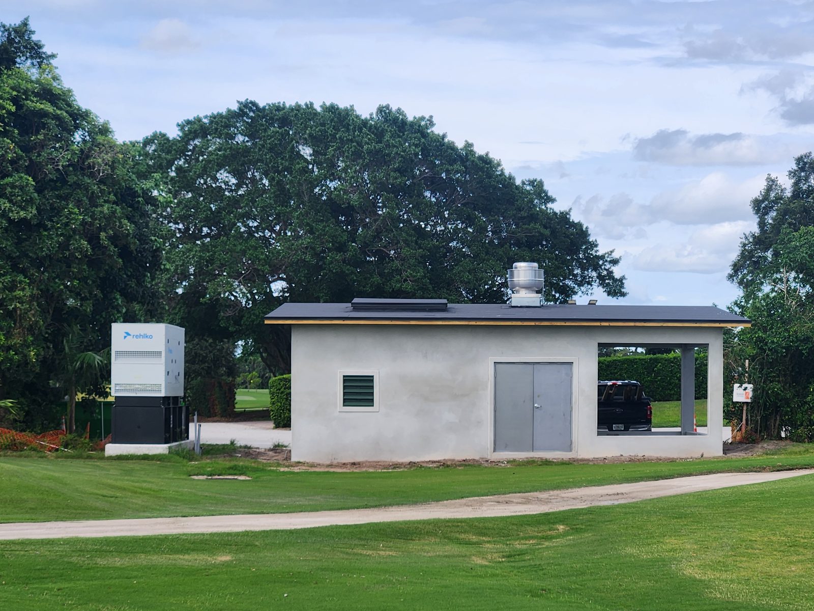 The finished Pine Tree Golf Club irrigation pumphouse with its enclosed pump room, covered equipment bay, and standby generator, set beside the course