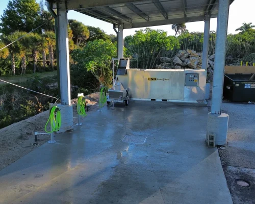 Covered wash pad interior with wash-water containment equipment, hose reels, and a finished concrete pad
