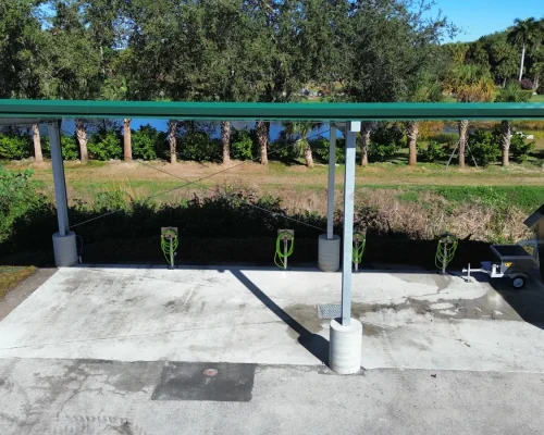 View beneath the wash pad canopy showing multiple hose stations along the sloped concrete pad