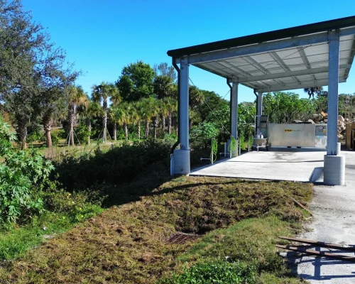 Side view of the finished covered wash pad showing the steel canopy, concrete pad, and containment equipment