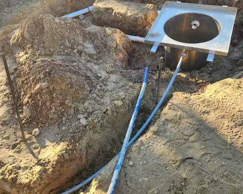 Stainless steel sump basin set into the ground with drainage lines during wash pad construction