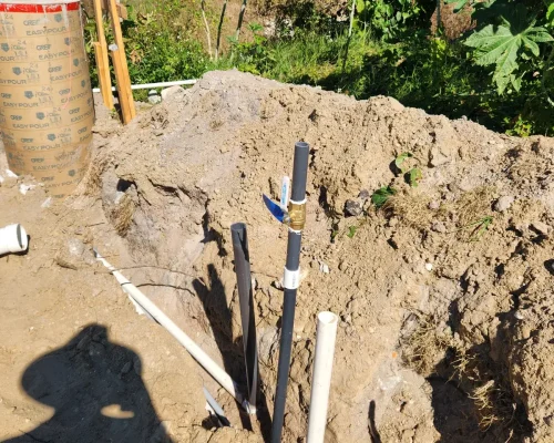 Utility and conduit rough-in in an excavated trench beside the wash pad footings