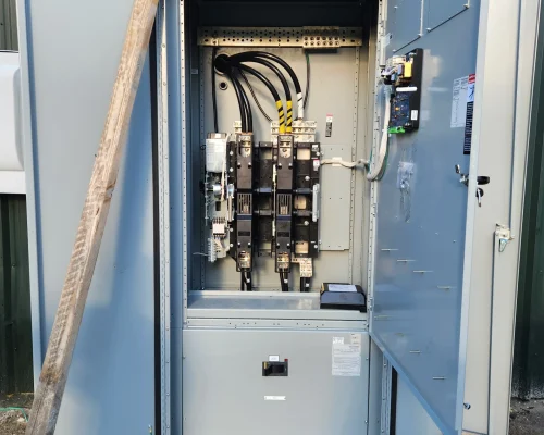 Deere excavator lifting electrical switchgear into outdoor enclosure