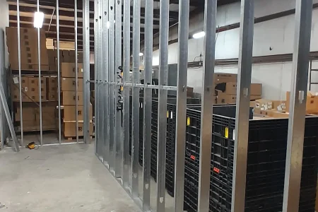 Metal-stud wall framing along warehouse storage shelving