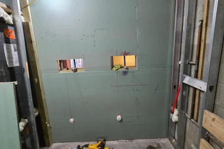 Green drywall partition with framed openings and reciprocating saw