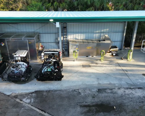 Aerial view of the completed Naples Heritage facility showing spray rigs parked under the covered wash pad, stainless wash station, and fuel area on freshly poured concrete.