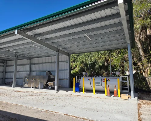 Completed steel canopy at Naples Heritage covering the fuel, wash, and mix load area, with a stainless mix station and fuel tank beneath the green-trimmed roof.