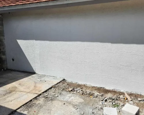 The rebuilt and refinished exterior wall of the Naples Heritage pump house, re-stuccoed and painted to match the existing structure with no sign of the opening.