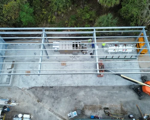 Overhead construction view of the Naples Heritage steel canopy frame being erected over the new concrete pad and wash station.