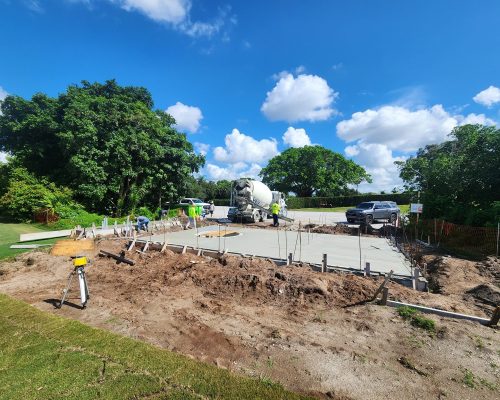Freshly poured concrete foundation slab for the new Pine Tree Golf Club pumphouse, with the wet well opening cast into the center and a concrete truck on site