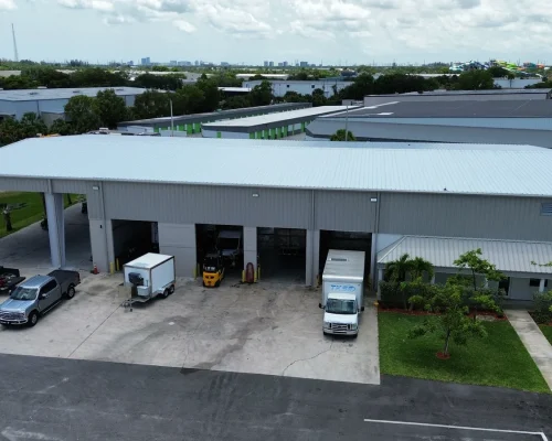 The finished extended Thermo King building with the covered service bay in use, vehicles parked beneath the new metal canopy.