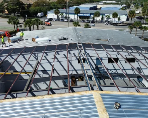 The Thermo King building mid-reroof, with old roofing stripped back and new structural steel and decking being installed.