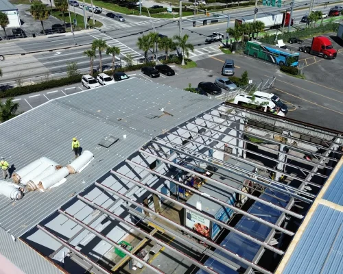 New steel roof framing erected over the Thermo King building during construction, with the old roof removed and crews working on the structure.
